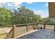 Wide wooden deck with railing and access to staircase featuring trees and sky background at 7606 Four Pines Rd, Plant City, FL 33565