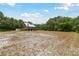 Exterior view of the raised home surrounded by an expansive, partially cleared yard at 7606 Four Pines Rd, Plant City, FL 33565