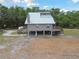 Two-story raised home featuring a metal roof, wraparound decks, and lush green surroundings at 7606 Four Pines Rd, Plant City, FL 33565