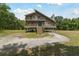 Inviting two-story home with wraparound porch, set on stilts, blending architectural design and outdoor living at 7606 Four Pines Rd, Plant City, FL 33565
