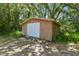 Outbuilding with a garage door, complemented by the natural beauty of surrounding trees at 7606 Four Pines Rd, Plant City, FL 33565