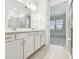 Bathroom featuring a double vanity, white cabinetry, and a glass-enclosed shower; bedroom view at 9530 Coastline Way, Parrish, FL 34219