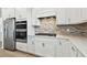 Modern kitchen featuring stainless steel appliances, white cabinets, a stylish backsplash, and a gas cooktop at 9530 Coastline Way, Parrish, FL 34219