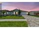 Charming home with a well-manicured lawn, paver driveway, and craftsman-style details under a twilight sky at 10317 Cross River Trl, Parrish, FL 34219