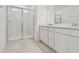 Bathroom with glass-enclosed shower, double vanity with white cabinets and quartz countertop at 10414 Cross River Trl, Parrish, FL 34219
