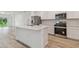 Bright, modern kitchen featuring an island with sink, stainless appliances, and wood-look flooring at 10414 Cross River Trl, Parrish, FL 34219
