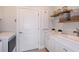 Clean laundry room with white cabinets, sink, quartz counters, shelving, and modern appliances at 10414 Cross River Trl, Parrish, FL 34219