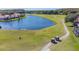 Aerial view of a beautiful lake and golf course with golf carts driving along the cart path at 1084 Berkshire Ln, Tarpon Springs, FL 34688