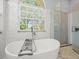 Bright bathroom featuring a freestanding soaking tub, a large window with natural light, and a glass-enclosed shower at 1084 Berkshire Ln, Tarpon Springs, FL 34688
