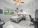 Cozy bedroom with a ceiling fan, window overlooking trees, tiled floors, and a comfortable bed and workspace at 1084 Berkshire Ln, Tarpon Springs, FL 34688