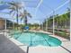 Sparkling screened-in pool and spa with a waterfall feature and lush landscaping at 1084 Berkshire Ln, Tarpon Springs, FL 34688
