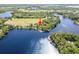 Panoramic aerial view showcasing the property’s location on the lake with lush surroundings highlighted with a red arrow at 18906 Crescent Rd, Odessa, FL 33556
