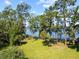 Expansive backyard with mature trees and lush green lawn, leading to tranquil lake views under a blue sky at 18906 Crescent Rd, Odessa, FL 33556