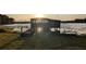 Rustic wooden boat house on stilts at sunset, overlooking the calm lake and lush treeline on a grassy lawn at 18906 Crescent Rd, Odessa, FL 33556