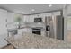 Modern kitchen showcasing white cabinetry, stainless steel appliances, and an island with granite countertops at 2166 Dixie Garden Loop, Holiday, FL 34690