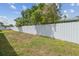 Backyard featuring a white picket fence, expansive lawn, and mature trees, perfect for outdoor enjoyment at 2305 W Kentucky Ave, Tampa, FL 33607