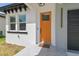 Home featuring a bright orange front door, stylish hardware, and a welcome mat at 2305 W Kentucky Ave, Tampa, FL 33607