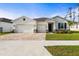 Charming single-story home with an attached three-car garage, paver driveway, and manicured lawn at 23243 Scaglione Dr, Lutz, FL 33549