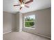 Neutral carpeted bedroom with ceiling fan and window view of wooded backyard at 2512 Clubhouse Dr, Plant City, FL 33566