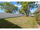 Large, grassy backyard enclosed by a white fence, with mature trees and a partial view of the house at 2961 Stockwood Dr, Clearwater, FL 33761