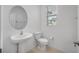 Bright half bathroom with a pedestal sink and a modern toilet under the window at 30752 Veridian Way, Wesley Chapel, FL 33545