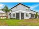 Back exterior view featuring a screen door, lush lawn, and well-maintained landscaping at 30752 Veridian Way, Wesley Chapel, FL 33545