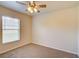 This vacant bedroom has carpet floors, a ceiling fan, and a window to allow plenty of natural light at 3206 Shalimar Ter, North Port, FL 34286