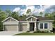 Inviting single-story home featuring a two-car garage, stylish architectural details, and lush landscaping at 3213 Lumber Falls Dr, Plant City, FL 33565