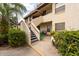 A walkway leads to a unit with covered entry, enhanced with greenery and a seating area at 3540 Countrybrook Ln # 23, Palm Harbor, FL 34684