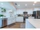 Bright kitchen featuring white cabinets, stainless steel appliances, an island, and a stylish white farmhouse sink at 3540 Countrybrook Ln # 23, Palm Harbor, FL 34684