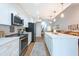 Open kitchen with stainless steel appliances, updated white cabinets and a stylish island with chairs at 3540 Countrybrook Ln # 23, Palm Harbor, FL 34684