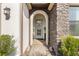 Arched entryway featuring a glass front door, stone accents, and manicured landscaping at 4365 Frontera Ln, Wesley Chapel, FL 33543