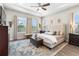 Luxurious main bedroom with a tufted headboard, neutral tones, wood-look floors, and ample natural light at 4365 Frontera Ln, Wesley Chapel, FL 33543
