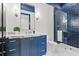 Stylish bathroom with blue vanity, marble countertop, and a glass-enclosed shower with dark blue tiling at 634 Poinsettia Rd, Belleair, FL 33756