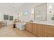 Bright bathroom with a soaking tub, double vanity, and a large mirror with sconces for enhanced lighting at 634 Poinsettia Rd, Belleair, FL 33756