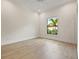 Bright, empty bedroom features hardwood floors and a large window with a view of lush greenery and palm trees at 634 Poinsettia Rd, Belleair, FL 33756