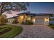 Stunning home exterior with elegant design, three-car garage, and brick driveway at 634 Poinsettia Rd, Belleair, FL 33756