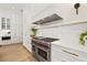 Bright kitchen with stainless steel Wolf range and oven, white cabinets, and white marble countertops at 634 Poinsettia Rd, Belleair, FL 33756