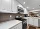 Modern kitchen featuring white cabinets, stone countertops, and stainless steel appliances at 7508 Hollowell Dr, Tampa, FL 33615
