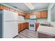 Bright kitchen features wood cabinets, white appliances, light countertops and gray wood flooring at 10906 Keys Gate Dr, Riverview, FL 33579