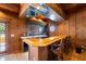 View of the basement bar area featuring elegant wood finishes, a mirrored backsplash, and seating for three at 11602 Innfields Dr, Odessa, FL 33556