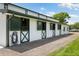 Exterior of the horse barn featuring green and white paint and stalls with partially opened doors at 11602 Innfields Dr, Odessa, FL 33556