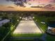 Well-lit equestrian arena at dusk with modern stables, horse paddocks, and adjacent farm house at 11602 Innfields Dr, Odessa, FL 33556