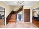 Elegant foyer with wood staircase, modern lighting fixture, tiled flooring and art sculpture adds to the home's appeal at 11602 Innfields Dr, Odessa, FL 33556