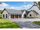 Spacious three-car garage with modern farmhouse design, black roof, and freshly paved driveway at 11602 Innfields Dr, Odessa, FL 33556