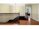 Hallway with hardwood floors, chandelier, white trim, and staircase creates a harmonious and inviting space at 11602 Innfields Dr, Odessa, FL 33556