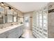 Bathroom featuring a double vanity, tile walls, and an eye catching glass block shower at 1513 Owen Dr, Clearwater, FL 33759