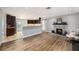 Open-concept living space featuring hardwood floors, a cozy fireplace, and a kitchen view at 1513 Owen Dr, Clearwater, FL 33759