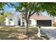 Charming white stucco home featuring a dark garage door and a well-maintained lawn with mature trees at 1608 Ledgestone Dr, Brandon, FL 33511