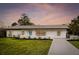 Well-maintained home featuring a vibrant turquoise front door, clean landscaping, and driveway at 1886 San Mateo Dr, Dunedin, FL 34698